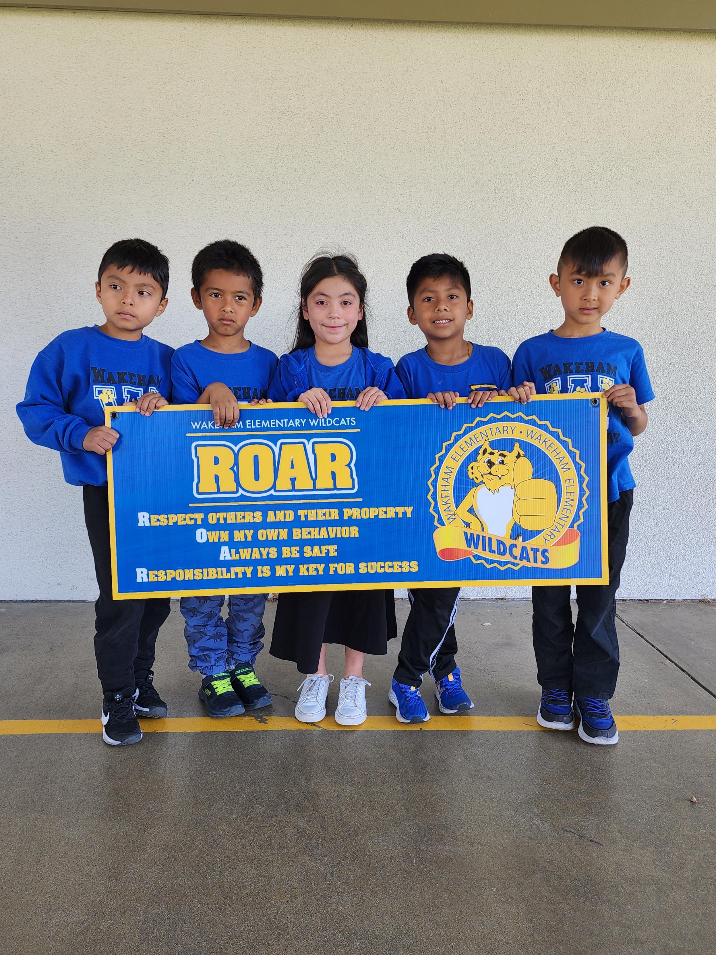 Wakeham scholars holding up the ROAR guidelines sign
