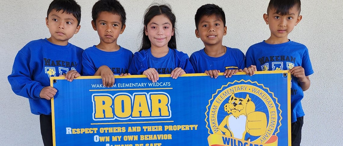 Wakeham scholars holding up the ROAR guidelines sign