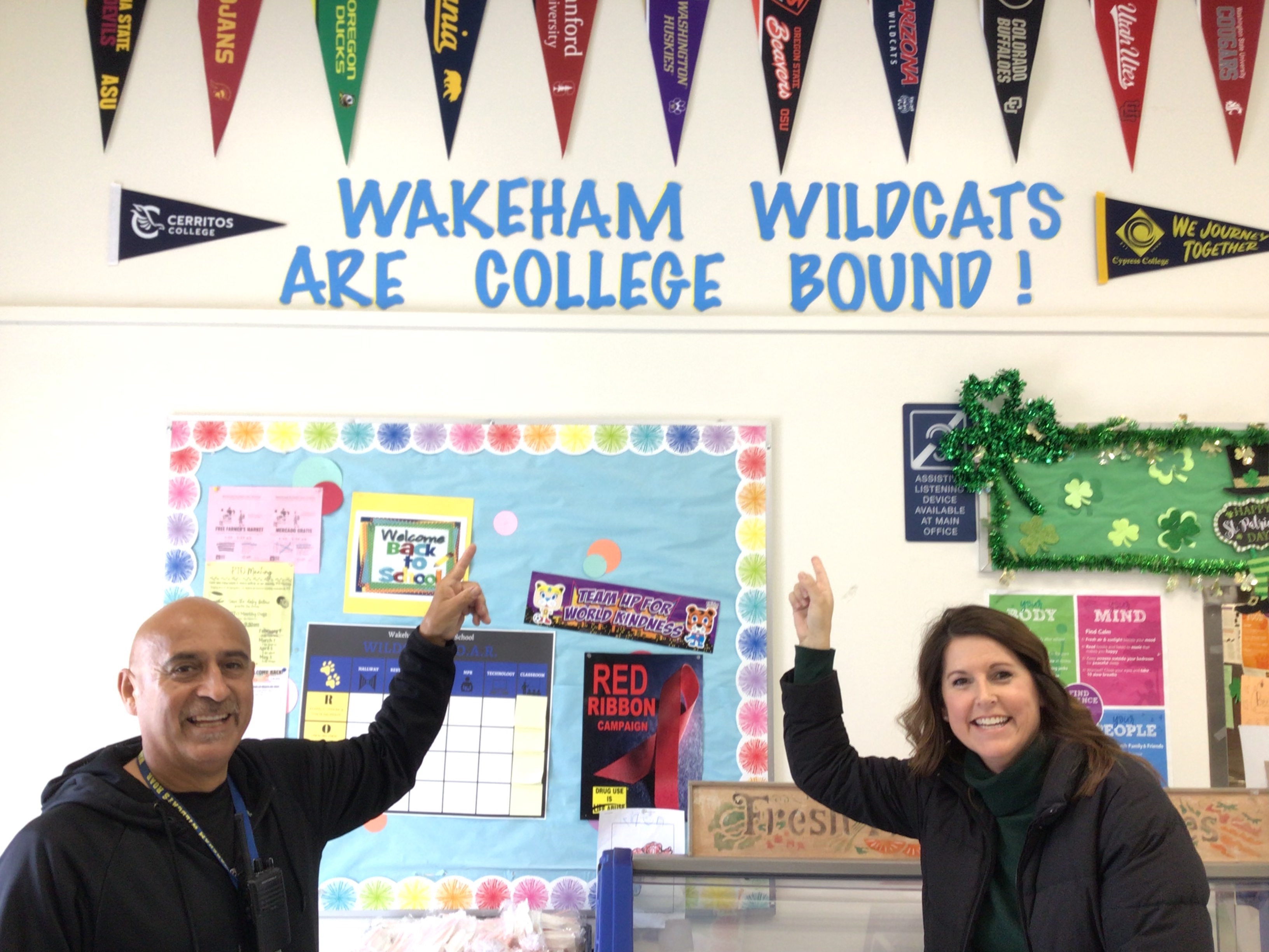Staff pointing at "Wakeham Wildcats are college bound!" decor