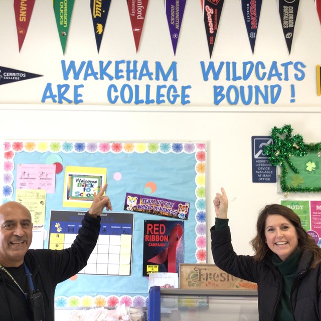 Staff pointing at "Wakeham Wildcats are college bound!" decor